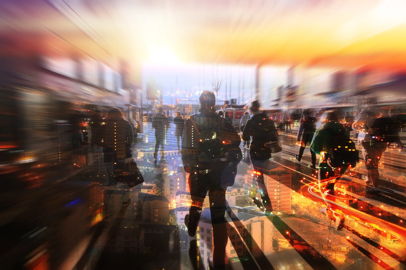 Commuters walking through a city street at sunset, blurred by motion.